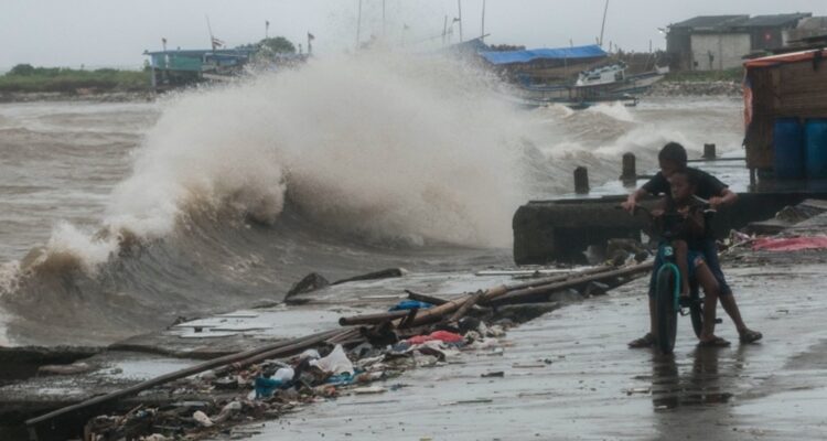 Anak bermain di sekitar jalan yang rusak akibat diterjang gelombang di Labuan, Pandeglang, Banten, Sabtu (27/11/2021).